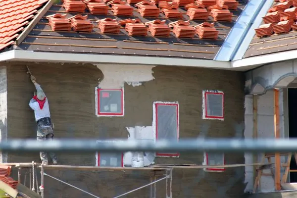 skilled stucco contractor applying stucco on exterior house