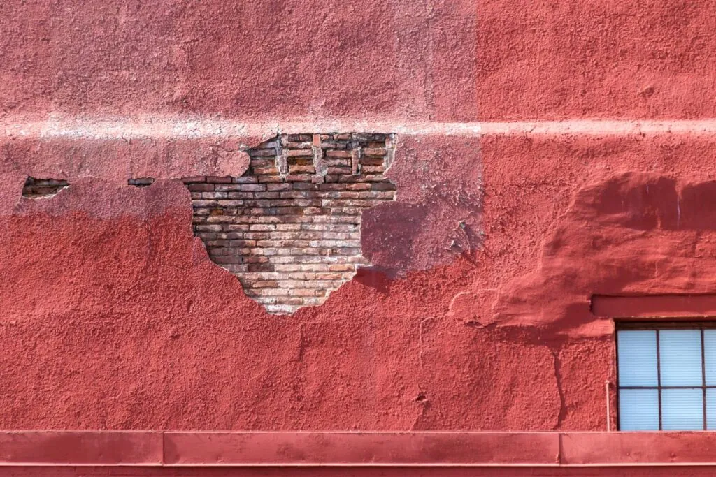 stucco wall revealing red brick